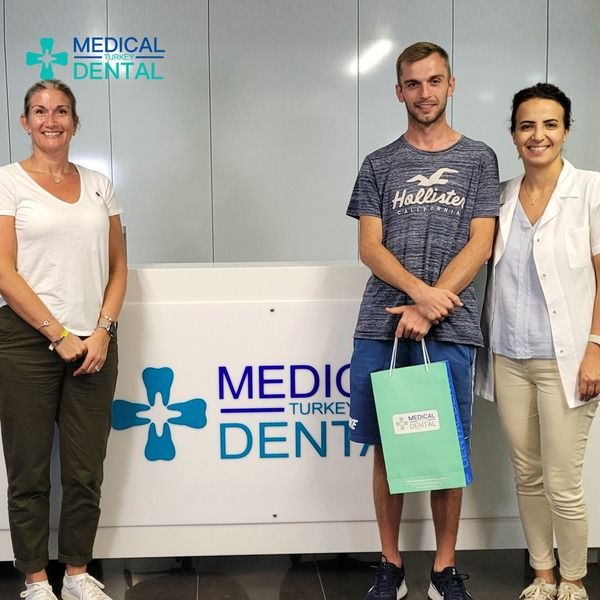 Dt. Zehra Uğur Nalbantçı standing next to the patients who had full dental implants